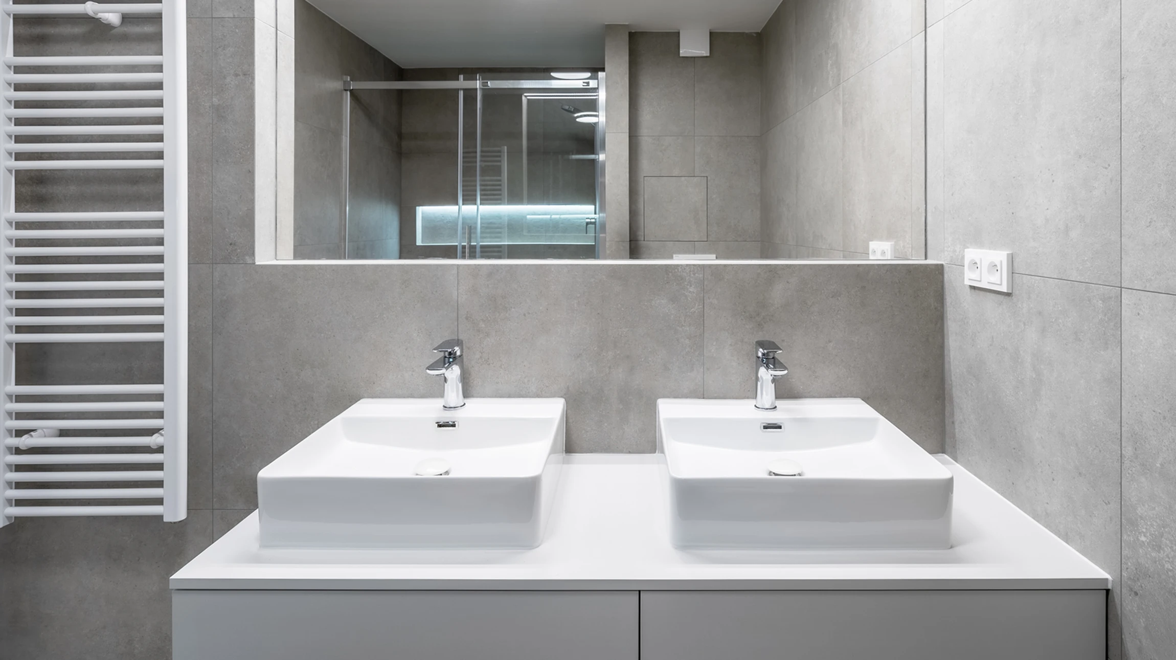 Salle de bain moderne avec douche à l'italienne vitrée, double vasque encastrée dans meuble laqué noir, miroirs encadrés avec éclairage LED intégré