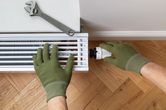 Local technique moderne avec chaudi&egrave;re murale blanche, ballon d'eau chaude vertical en inox, circuit de distribution avec collecteur &agrave; vannes rouges et tubes noirs isol&eacute;s