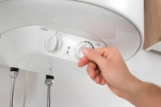Vue d&eacute;taill&eacute;e et rapproch&eacute;e d'un plombier professionnel effectuant l'installation d'un chauffe-eau &eacute;lectrique ou thermodynamique dans un local technique r&eacute;sidentiel. L'artisan, &eacute;quip&eacute; d'outils appropri&eacute;s, doit &ecirc;tre en train de raccorder les tuyauteries d'arriv&eacute;e et de distribution au chauffe-eau. Le r&eacute;servoir doit &ecirc;tre clairement visible, de type moderne et professionnel. L'environnement doit montrer un espace technique r&eacute;el (cave, cellier ou local technique) avec des conduites, des vannes et un travail en cours pr&eacute;sent&eacute; de mani&egrave;re s&eacute;rieuse et professionnelle.